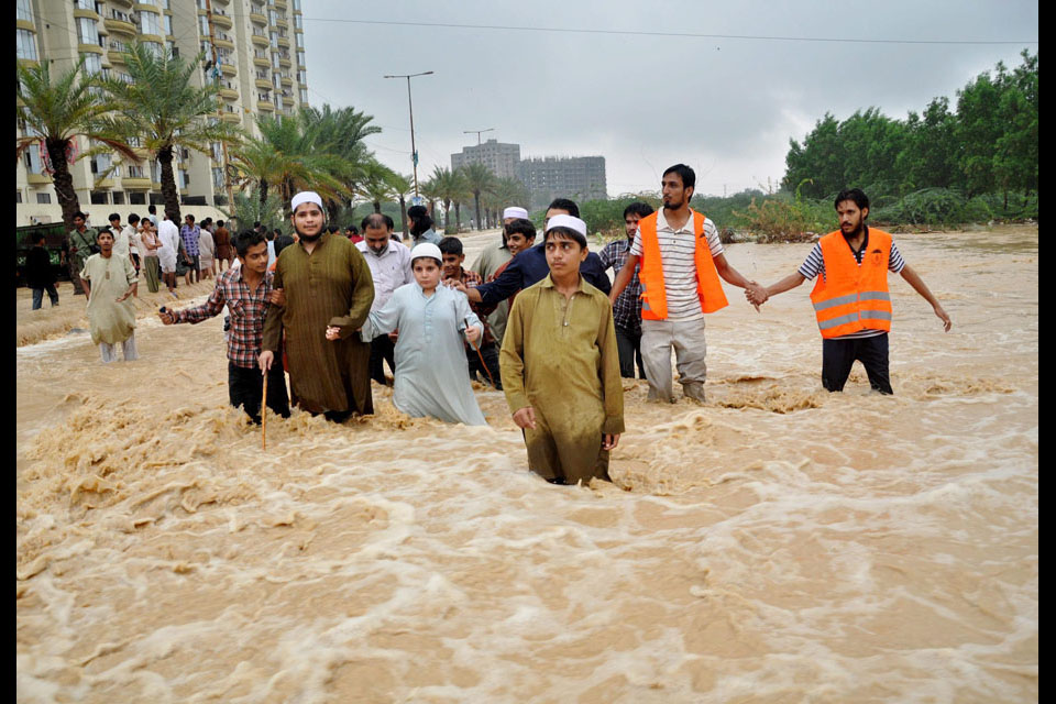 People evacuate flooded areas following heavy rains in Karachi