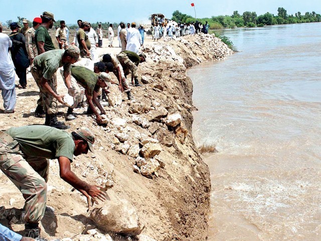 Pakistan Army officials dump stones to strengthen the embankment along River Indus at Aqil Agani