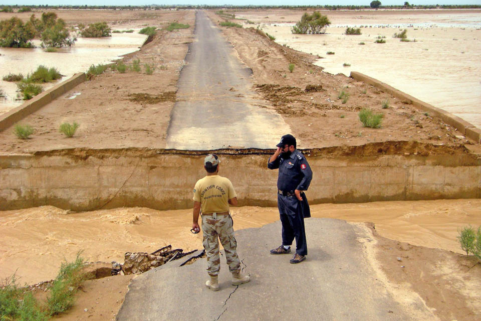 Pakistani security officials inspect a damaged road following rain and flooding in Jhal Magsi, Balochistan province
