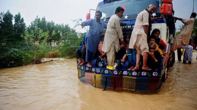 Pakistani residents ride on a truck as they evacuate a flooded area in Karachi