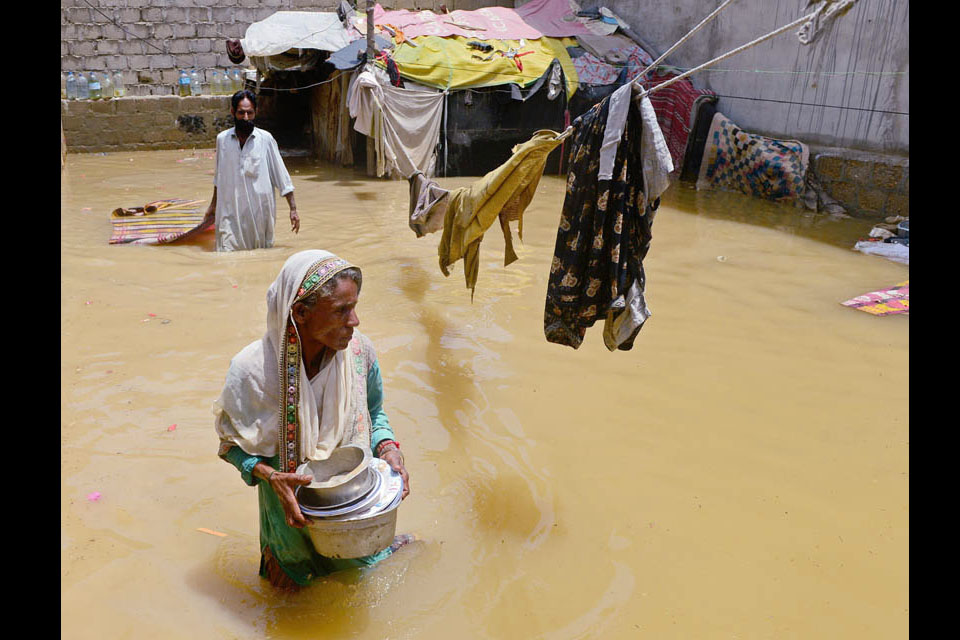 A woman wades through flood waters following a heavy monsoon in Karachi