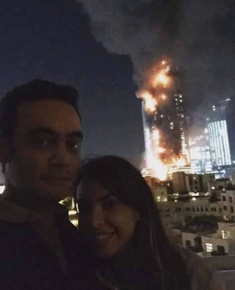 Couple clicks selfie with a burning Hotel  in the background
